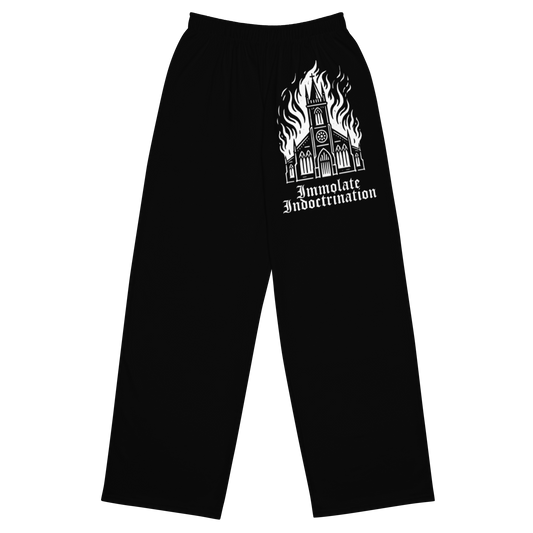 white design on black wide legged lounge pants of an illustrated burning church with the words immolate indoctrination in older goth font below