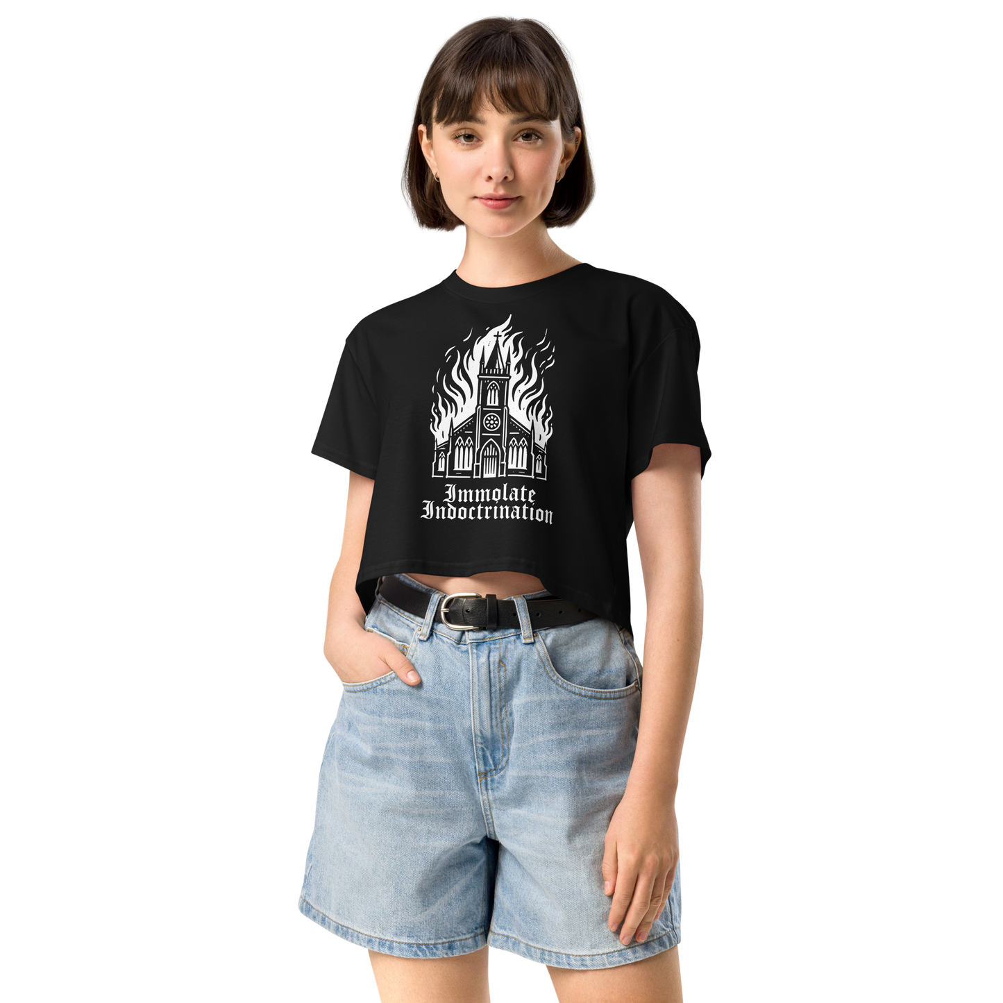 white design on black womens croptop of an illustrated burning church with the words immolate indoctrination in older goth font below
shown on a thin framed woman