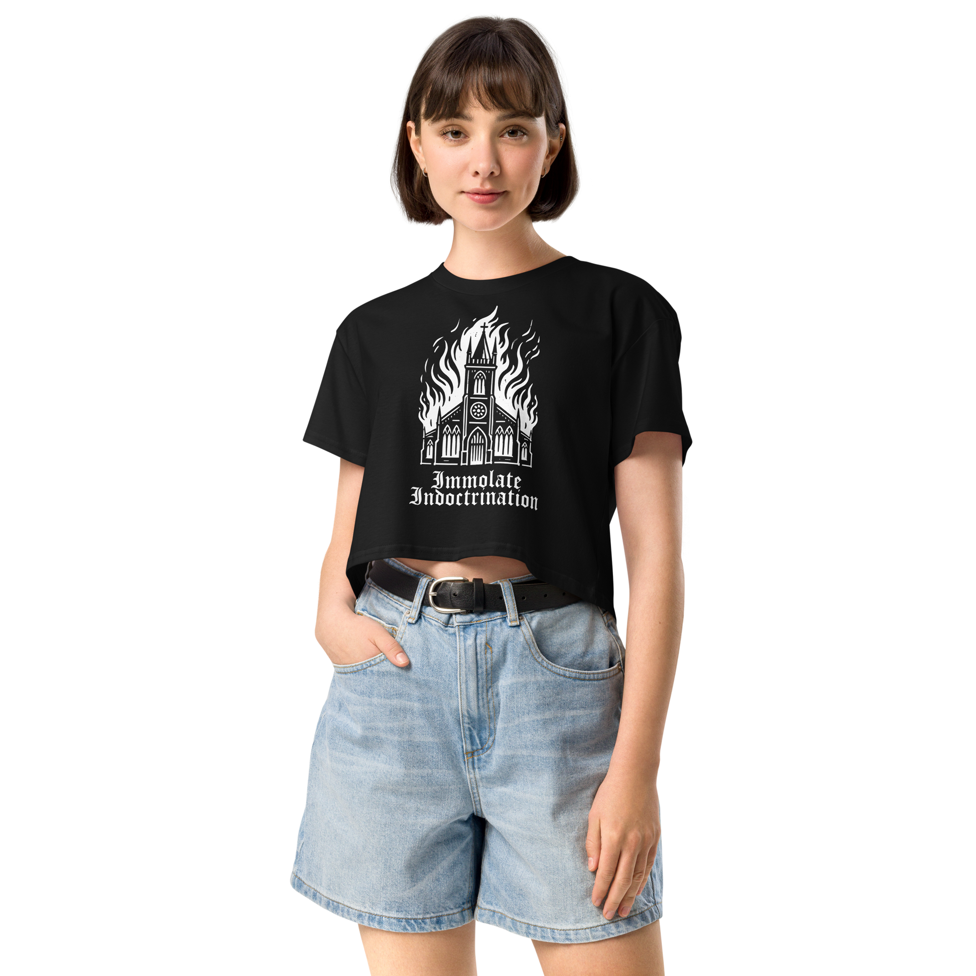 white design on black womens croptop of an illustrated burning church with the words immolate indoctrination in older goth font below
shown on a thin framed woman