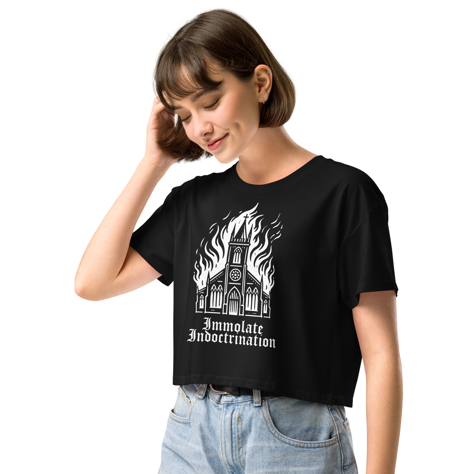 white design on black womens croptop of an illustrated burning church with the words immolate indoctrination in older goth font below
shown on a thin framed woman